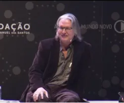 Bruce Sterling a falar, no palco da Casa da Música do Porto, sobre um fundo com o logo da Fundação Francisco Manuel dos Santos.