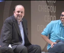 Três homens a debater num painel, durante um evento. Texto ao fundo.