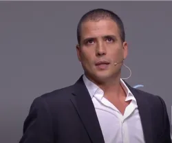 Ricardo Araújo Pereira, de fato, a falar ao microfone, durante um evento. No canto direito, o logotipo da Fundação (FFMS)