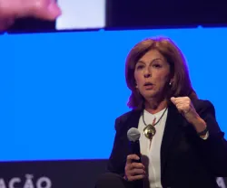 Imagem de mulher a falar num evento, com o texto "FUNDAÇÃO" visível ao fundo.