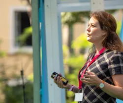 A economista Martha Bailey a discursar, de pé, com um jardim de fundo.