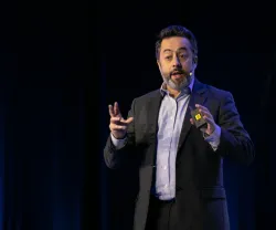 O professor de Ciência Política Tiago Fernandes a falar em palco. Fundo escuro.
