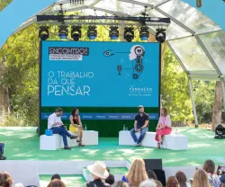 Evento ao ar livre com painel de discussão. Texto: "O TRABALHO DÁ QUE PENSAR".