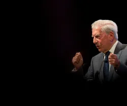 Mario Vargas Llosa a discursar. Fundo escuro.