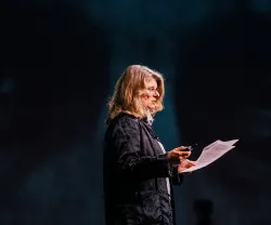 Alice Ramos, em palco, a discursar com papéis nas mãos.