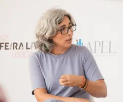 Mulher com cabelo grisalho e óculos, a falar num debate da Feira do Livro de Lisboa.
