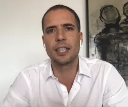 O humorista Ricardo Araújo Pereira fala para a câmera, com um quadro ao fundo.