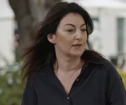Mulher de cabelo escuro sentada num banco de jardim.