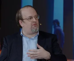 O cronista Pedro Mexia sentado, a falar enquanto gesticula. Fundo com luzes azuis.