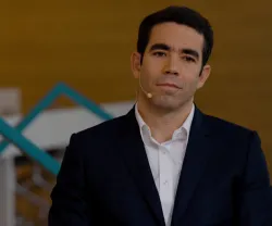 Homem (António Leitão Amaro) com um microfone, vestido de fato escuro e camisa branca, sem gravata.