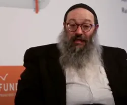 Homem com barba e óculos, a falar durante uma entrevista. Fundo com texto "FFMS.