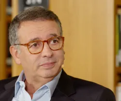 António José Seguro, com óculos, sentado, numa biblioteca. Fundo com prateleiras de livros.