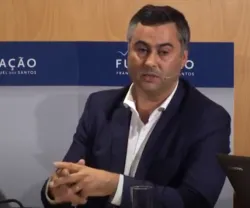Fernando Alexandre, vestido com um fato preto e camisa branca, a falar num painel, com a logo da "FUNDACÃO" ao fundo.