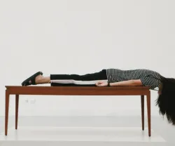 Uma pessoa deitada de barriga para baixo sobre uma mesa de madeira.