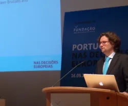 Alexander Trechsel a falar com diapositivos sobre decisões europeias a aparecer ao fundo.