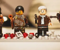 Figuras de LEGO de quatro personagens com armas, em fundo claro.