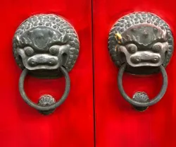 Portas vermelhas com puxadores de metal em forma de leões chineses.