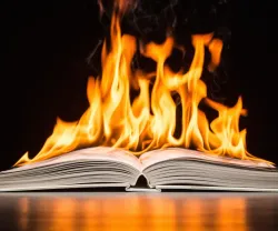 Livro aberto com chamas intensas em cima das páginas.