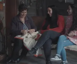 Uma mãe a conversar com as filhas adolescentes enquanto costura.