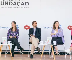 Imagem de uma palestra com cinco pessoas sentadas em cadeiras, com o logotipo da Fundação ao fundo.
