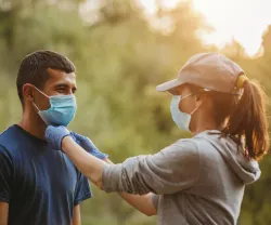 Imagem de um casal a caminhar numa floresta com uma máscara de proteção