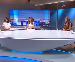 Cinco oradores num estúdio da televisão, sentados à volta de uma mesa moderna. 