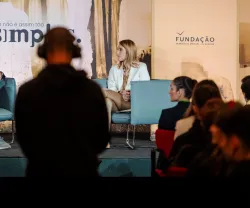 Evento com dois oradores no palco. O da direita é Roberta Metsola. Texto "Isto não é assim tão simples".