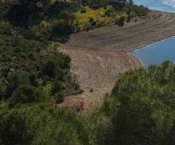 Vista aérea da costa da Barragem de Odeleite, com água e vegetação.