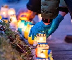 Imagem de uma pessoa a colocar velas em memória dos mortos