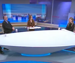 Cinco pessoas sentadas à volta de uma mesa oval num estúdio de televisão.