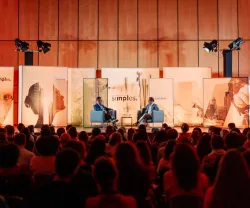Um evento com um público sentado, duas pessoas em palco, uma delas o sociólogo Hein de Haas.