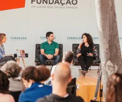 Imagem de um painel com quatro participantes, com uma plateia. Logotipos "Fundação" e "Praça da Fundação".