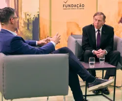 David Petraeus sentado, à frente de um jornalista, a ser entrevistado em Lisboa