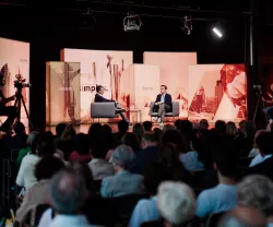 Evento com público sentado, e Peter Frankopan, em palco, a ser entrevistado por um jornalista. 