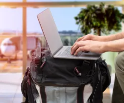 Imagem de uma pessoa a trabalhar no computador, no aeroporto, para ilustrar o artigo sobre nómadas digitais