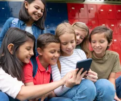 Um grupo de crianças na escola a utilizar smartphones e as redes sociais