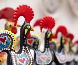 Imagem de várias figuras em barro do galo de Barcelos, numa loja de artigos para turistas.