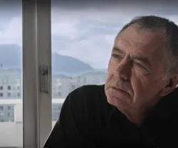 O filósofo e sociólogo Gilles Lipovetsky com ar pensativo, junto a uma janela com montanhas ao fundo.