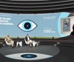 Carlos Fiolhais e outro homem sentados, num estúdio de televisão, a olhar para uma tela, na qual Ann Druyan está a falar.