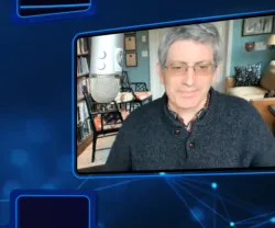 Uma tela que projeta Carl Zimmer, com o cabelo grisalho, a usar uma camisola escura, sentado.