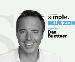 Retrato a preto e branco de Dan Buettner, com texto "BLUE ZONES" ao lado.