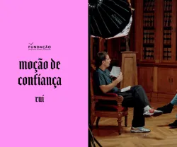 Guilherme Geirinhas sentado ao lado de Rui Tavares. Texto "moção de confiança" sobre um fundo rosa.