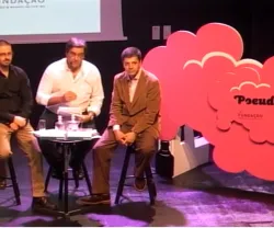 Três homens sentados em cadeiras durante um evento sobre "Pseudociência".