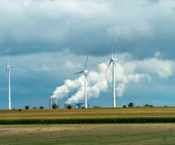  Turbinas eólicas e tubos industriais com fumo a sair num dia nublado na Alemanha. Créditos shutterstock