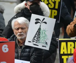 Uma manifestante em NY a segurar um cartaz com uma ilustração da estátua da liberdade a agarrar uma torre de petróleo. Créditos: shutterstock