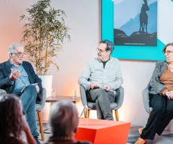 Uma plateia sentada a ouvir um debate entre quatro pessoas que estão em palco.