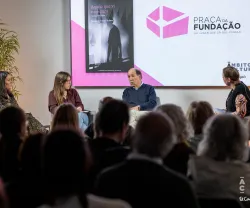Quatro pessoas sentadas em palco a debater. Ao fundo, uma tela com a capa do livro da Fundação «Aquilo que Vi no Escuro, Histórias sobre a psicose».