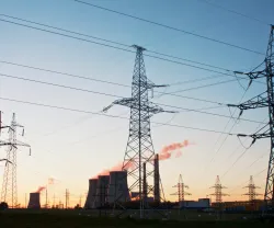 Uma paisagem com torres de refrigeração e uma central elétrica, tendo como fundo um céu azul. Crédito: Shutterstock