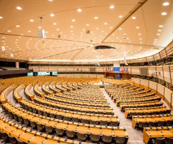 Imagem do interior do Parlamento Europeu. Ao fundo, as bandeiras de cada um dos Estados-membros.