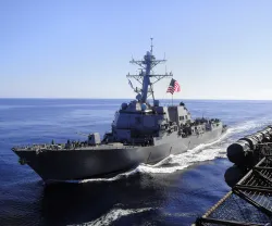 Imagem de um barco da marinha americana, com uma bandeira dos EUA hasteada.